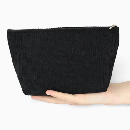 Trousse de toilette femme posée dans bagage, matière souple et légère en velours