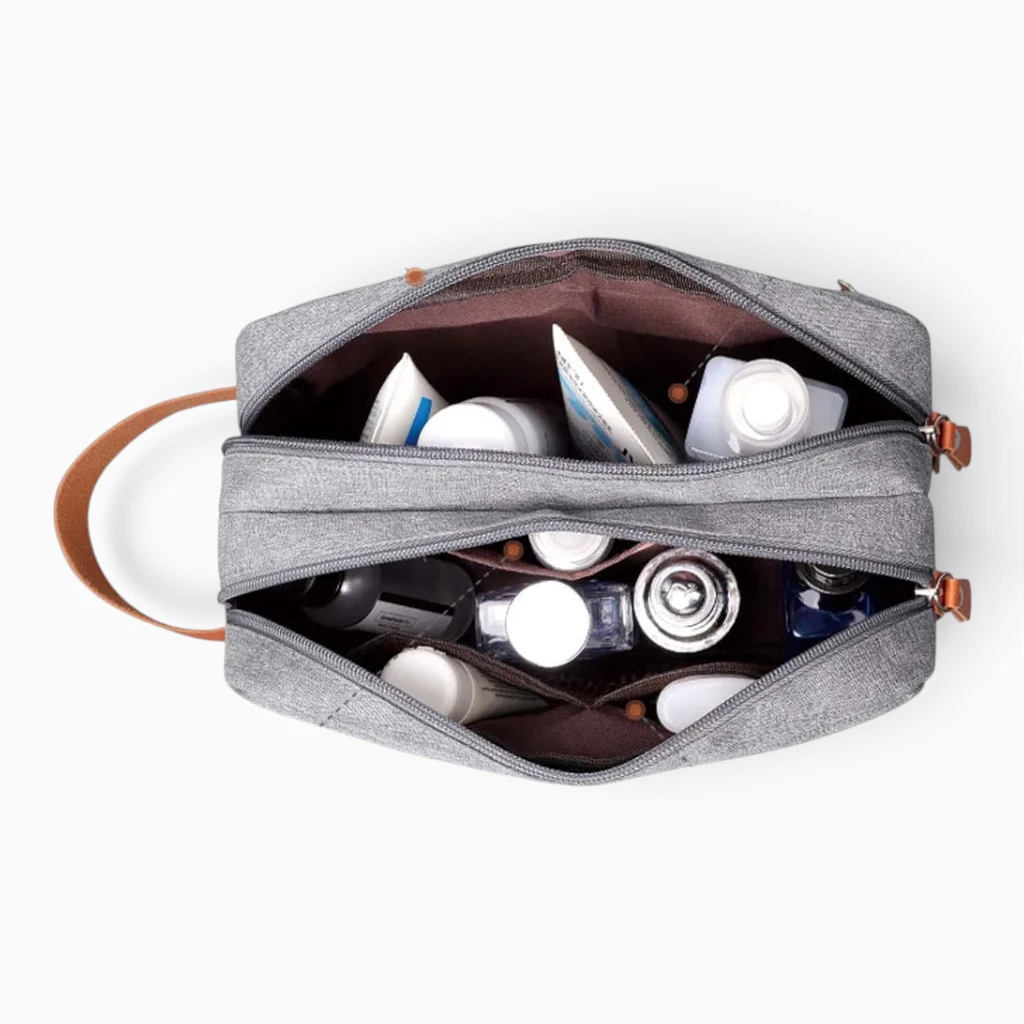 Petite trousse de toilette bleu foncé parmi articles de voyage, intégration discrète dans bagages et affaires