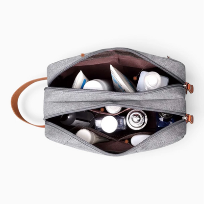 Petite trousse de toilette bleu foncé parmi articles de voyage, intégration discrète dans bagages et affaires