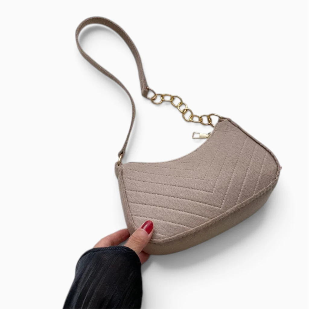 Sac bandoulière marron forme demi-lune porté sous le bras en tenue décontractée